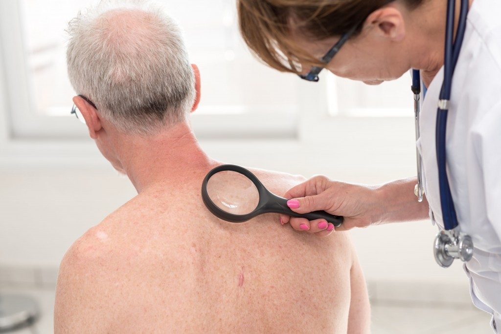 doctor examining back of an old guy