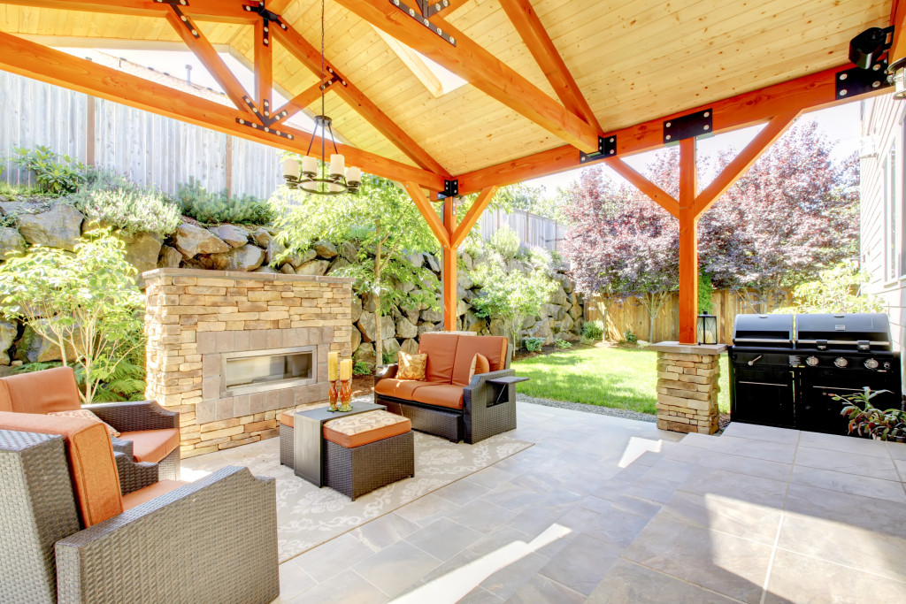 Exterior covered patio with fireplace and furniture. Wood ceiling with skylights